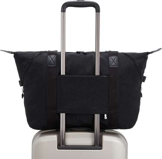 Sac Kipling ART M noir avec poignées et passant pour trolley, sur une valise argentée.