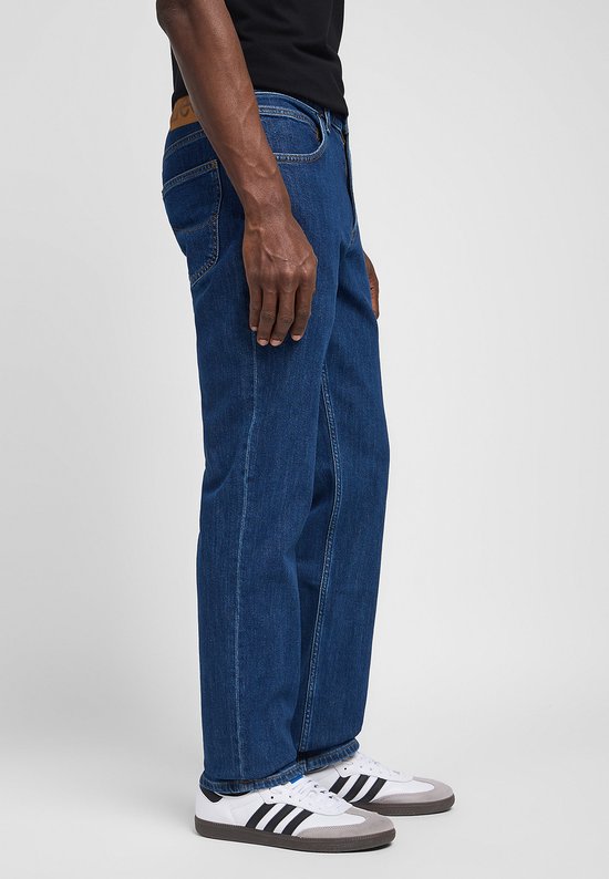 Man in donkerblauwe Lee jeans met rechte pasvorm, van de zijkant gezien, met Adidas sneakers.