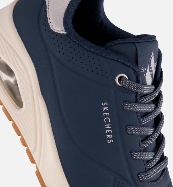 Close-up van de zijkant van de Skechers sneaker, toont het merklogo en de perforaties in het blauwe materiaal.