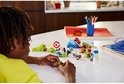 Een jongen met een gele trui die een LEGO Sonic speelset bouwt met Sonic, een lanceerbaan en hindernissen.