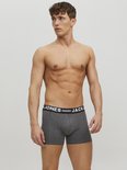 Grijze boxer met zwarte elastische band met witte tekst: JACK & JONES, gedragen door een man.