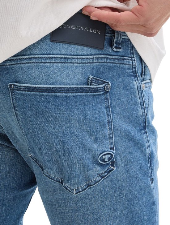 Close-up van blauwe Tom Tailor jeans met leren logo patch.