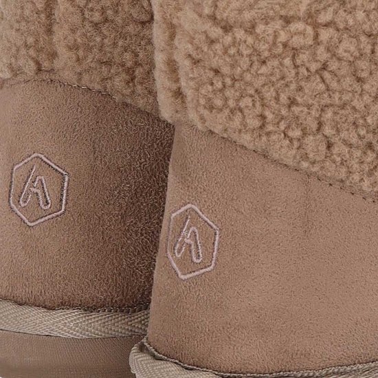 Close-up van de beige suède hiel met subtiel ingedrukt logo op bruine teddy enkellaars pantoffels.