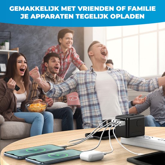 Zwarte wereldstekker op tafel, laadt 4 telefoons op terwijl vrienden juichen op de bank.