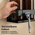 Hand die een verstelbare haak aan een zwart doucherekje bevestigt met een scheermesje eraan.