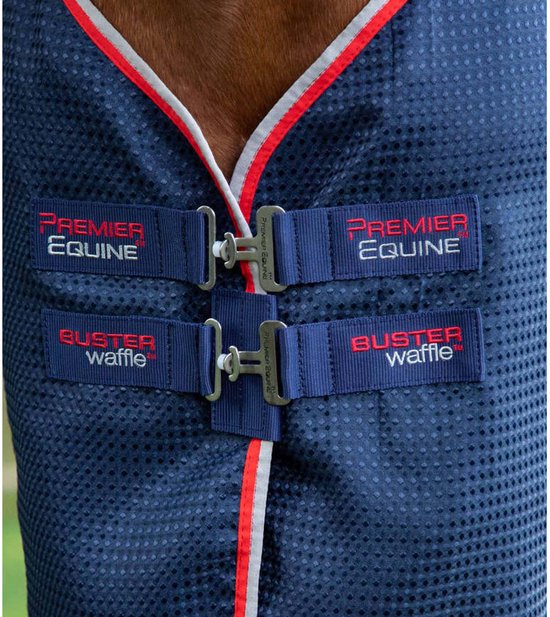 Donkerblauwe paardendeken met dubbele sluiting en rode en grijze bies. Premier Equine Buster Waffle logo's.