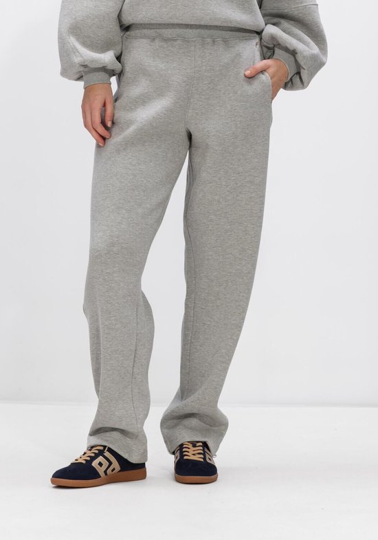 Grijze joggingbroek met wijde pijpen en een model dat hem draagt met sneakers.