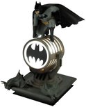 Batman-figuur bovenop een verlichte lamp met vleermuislogo, met vleermuisdecoraties aan de basis.