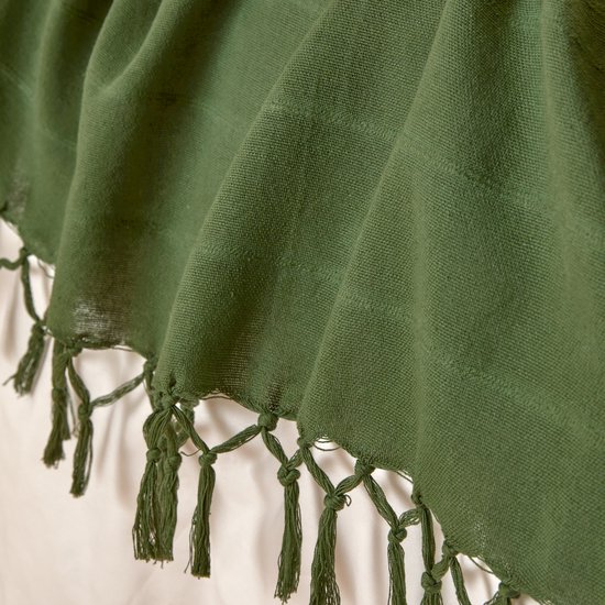 Gedetailleerde close-up van een donkergroene plaid met gedraaide franjes aan de zoom.