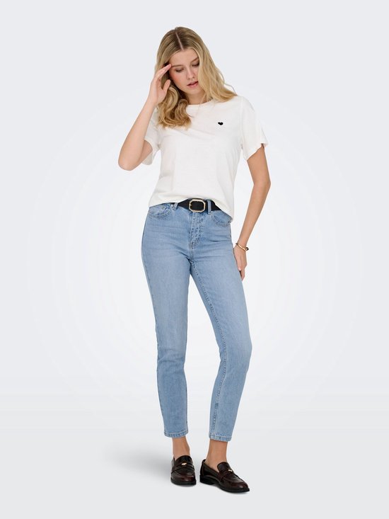 Vrouw met een witte t-shirt en blauwe jeans met rechte pijpen, hoge taille en riem.
