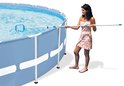 Een vrouw met een zomerjurk gebruikt een schepnet om een zwembad schoon te maken.