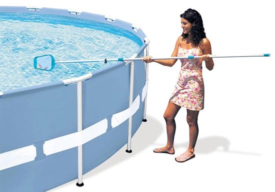 Een vrouw met een zomerjurk gebruikt een schepnet om een zwembad schoon te maken.