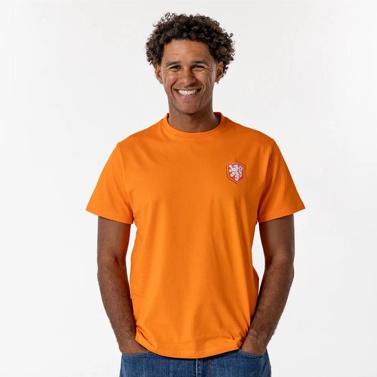 Lachende man in oranje T-shirt met korte mouwen en opgestikte badge op linkerborst.