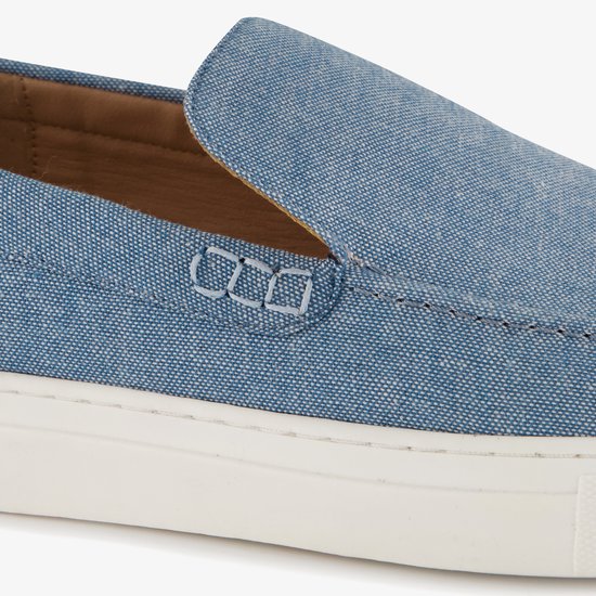 Blauwe denim instapper met witte stiksels op de neus en een witte zool.