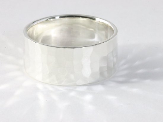 Bague large en argent martelé avec une finition brillante.