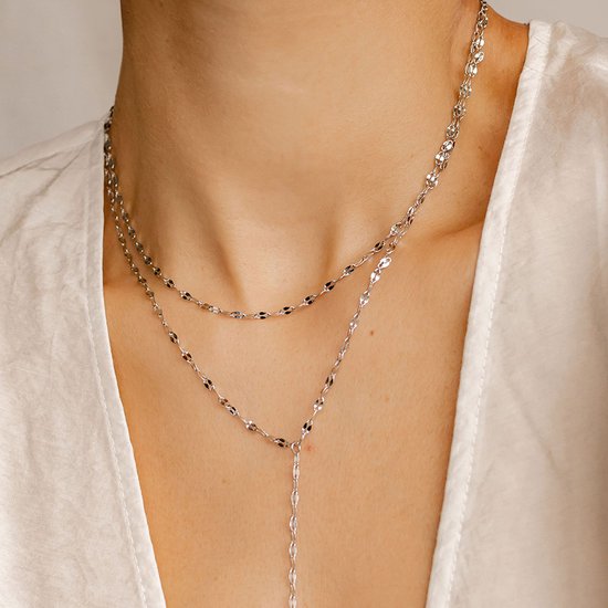 Zilverkleurige gelaagde ketting met platte schakels en een Y-vormige drop, gedragen door een model.