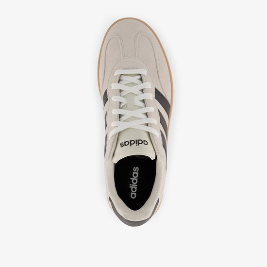 Bovenaanzicht van een beige Adidas sneaker met witte veters, zwarte strepen en een gumkleurige zool. Adidas logo op de binnenzool.