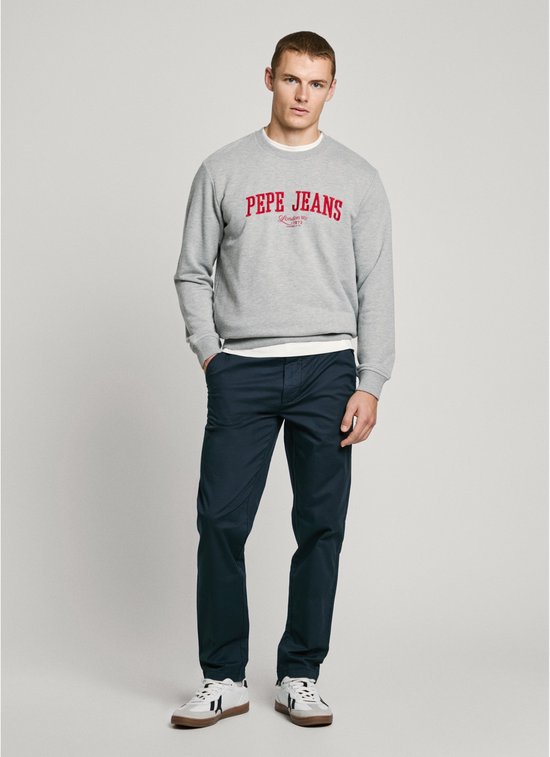 Model draagt donkerblauwe chino en Pepe Jeans grijze sweater.