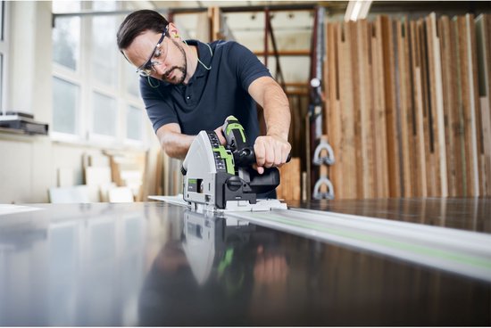 Homme avec lunettes de sécurité et protection auditive utilise une scie plongeante Festool TS 55 FEBQ sur un établi.