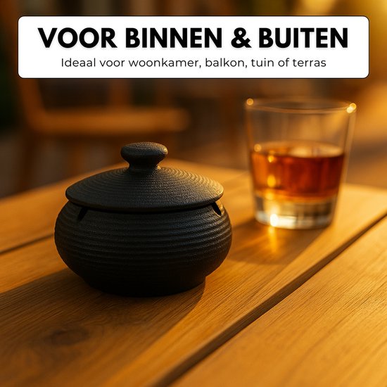 Zwarte, geribbelde keramische asbak met deksel op houten tafel, naast een glas.