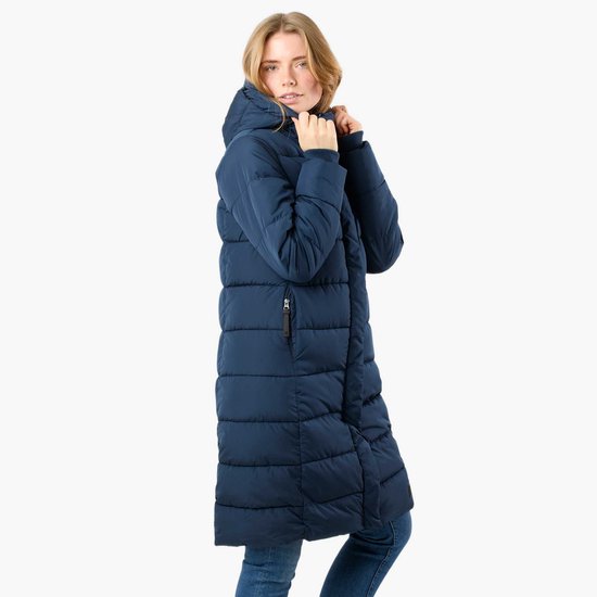 Vrouw in een lange, donkerblauwe, gewatteerde winterjas, de zijkant zichtbaar. Ze trekt de capuchon aan.