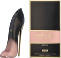 Zwarte parfumdoos met roze band en 'Good Girl Blush Elixir' tekst. Naast een stiletto parfumfles in zwart en roze met gouden hak.