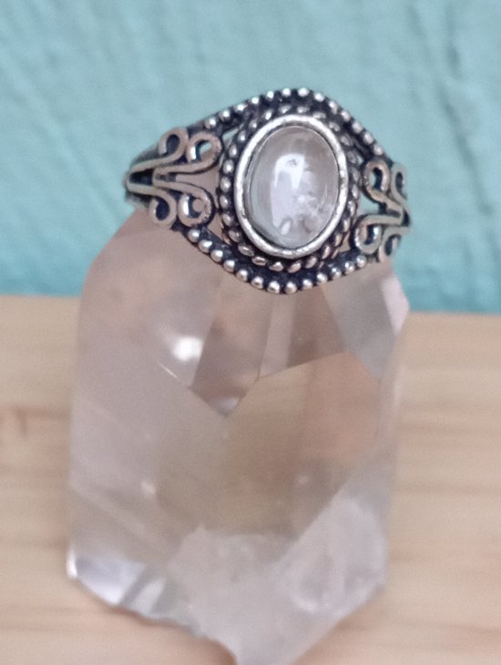 Bague argentée avec une pierre ovale claire et un monture détaillé.