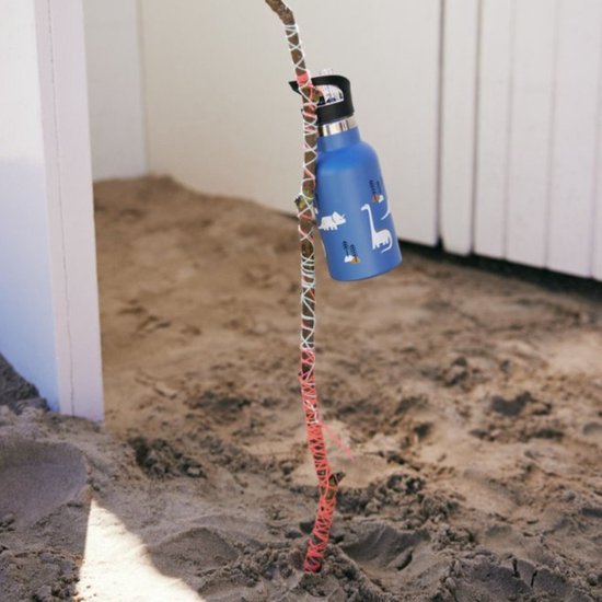 Blauwe drinkfles met dinosaurusprint, hangend aan een stok in het zand.