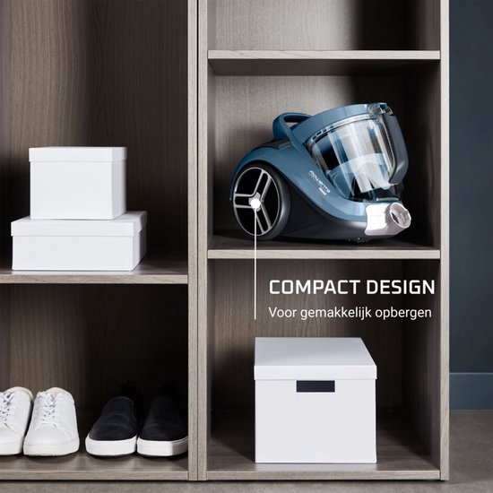 Aspirateur bleu sur une étagère dans une armoire, texte "DESIGN COMPACT".
