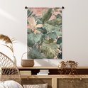 Wandkleed met tropische bladeren in groen en roze tinten, op een dressoir.