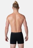 Achterkant van een man met strakke rugspieren, draagt een zwarte Muchachomalo boxer.