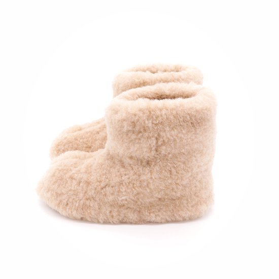 Hoge beige wollen sloffen met bruine zolen, half van voren gezien.