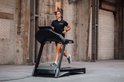 Vrouw met paardenstaart rent op een loopband in zwart Focus Fitness shirt en zwarte broek.