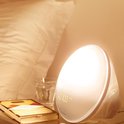 Philips wek-up light op een nachtkastje naast een boek en een glas water, met de tijd 07:00 weergegeven.