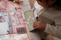 Meisje speelt met een stickerboek met kamers, meubels en figuren.