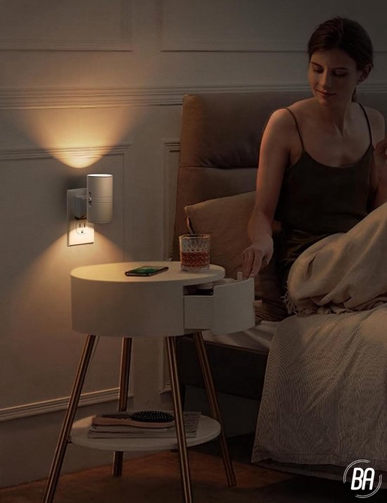 Wit nachtlampje in een stopcontact verlicht een slaapkamer, een vrouw zit op bed.