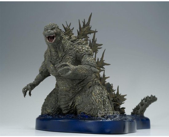 Grijze Godzilla figuur met scherpe rugplaten, knielend op een blauwe waterbasis.