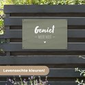 Donkergroene banner met witte tekst 'Geniet - Meer Niet -' en een hartje, hangend aan een donkerhouten schutting.