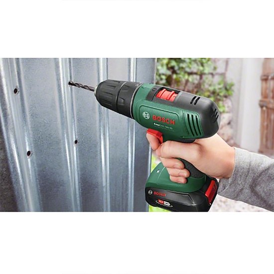 Hand met Bosch EasyDrill 18V-40 accuboormachine boort in metalen plaat.