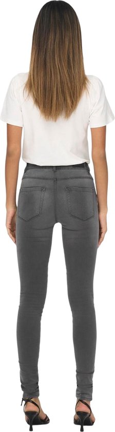 Model draagt een grijze skinny jeans met witte top, achterkant zichtbaar.