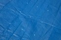 Gedetailleerde textuur van een blauw Bestway zwembadafdekzeil met meerdere lichte vlekken.