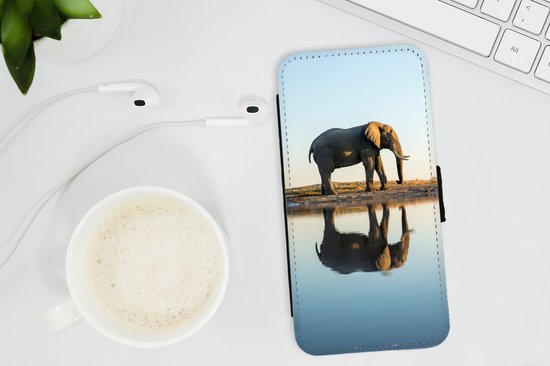 Zwarte portemonnee telefoonhoes met een olifant bij een waterplas, op een bureau naast een kop koffie.