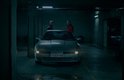 Twee mannen praten in parkeergarage bij zilverkleurige sportauto.