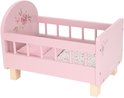 Leeg roze poppenbedje met bloemenmotief en houten pootjes.