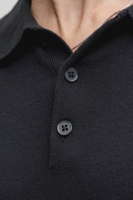 Close-up van de knoopjes van een zwart gebreid poloshirt.
