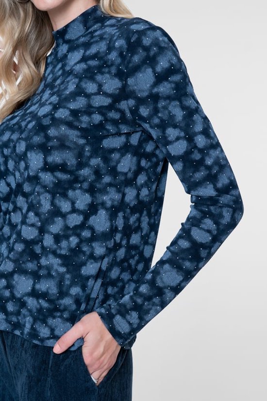 Detail van een blauwe top met all-over dierenprint en kleine witte stipjes.