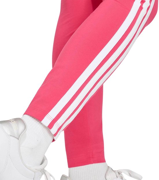 Roze adidas legging met witte zijstrepen, gecombineerd met witte sokken en witte sneakers.