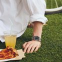 Persoon in wit shirt draagt een zilveren Citizen Tsuyosa horloge met zwarte wijzerplaat in het gras.