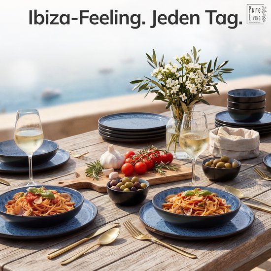 Gedekte tafel bij de zee met blauw servies, pasta, wijn en olijven. "Ibiza-Feeling. Elke Dag."