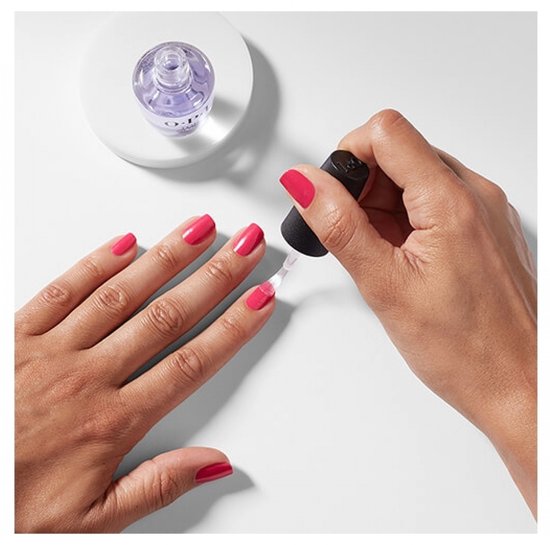 Hand brengt roze nagellak aan met O.P.I. top coat. De nagels zijn gelakt in een felle roze kleur.